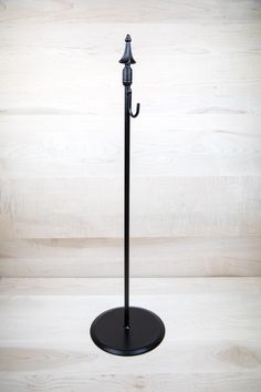 an umbrella stands on a black stand against a white background with wood grained walls