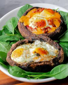 two baked potatoes with spinach leaves and eggs on them are sitting on a plate