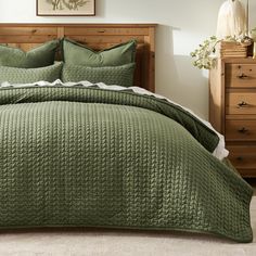 a bed with green bedspread and pillows