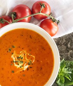 a bowl of tomato soup next to some tomatoes