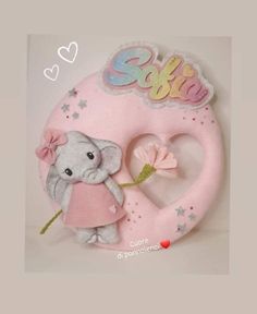 a stuffed elephant holding a flower in front of a heart shaped sign with the word sister written on it