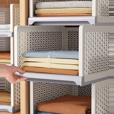 a person is reaching for some folded cloths on a shelving unit in a closet