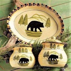 two ceramic dishes with bears painted on them and pine cones in the foreground, against a green wood background