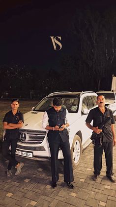 three men standing in front of a white car