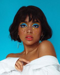 a woman with blue and gold makeup looks at the camera