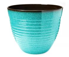 a teal colored vase is sitting on a white surface with black rim and bottom