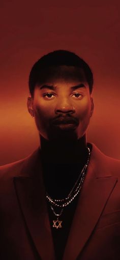 a man in a suit and necklace looking up at the camera with an intense look on his face