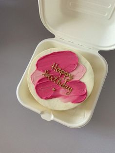 a birthday cake with pink frosting in a foam container