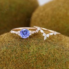 a tan and white gold ring with an oval blue sapphire surrounded by diamonds on moss