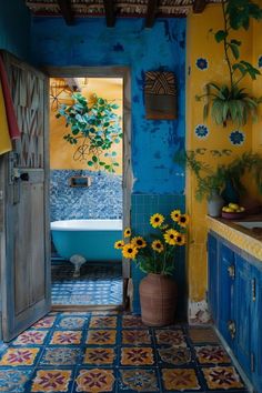 a blue and yellow bathroom with sunflowers in the bathtub next to it