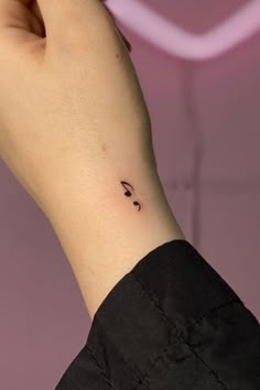 a woman's wrist with a smiley face tattoo on the left side of her arm