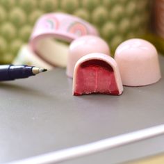 two pieces of pink candy sitting on top of a table next to a marker and pen