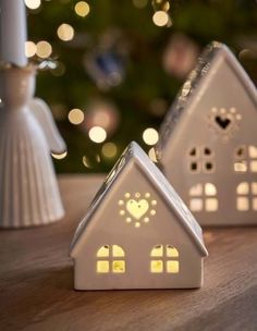 two small white houses sitting on top of a wooden table next to a christmas tree