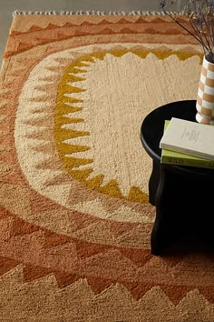 a living room area with a rug, coffee table and vase on the end table