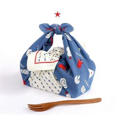 a blue bag with red and white designs on it next to a wooden utensil