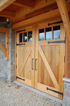 two wooden doors are open in front of a stone wall and wood frame entrance to a home