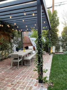 an outdoor dining area with brick patio and pergolated roof, surrounded by greenery