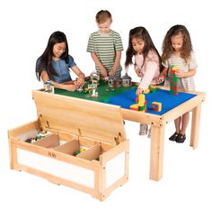 three children playing with legos on a wooden table and two storage bins under the table