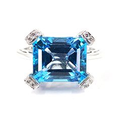 This ring is crafted in 18 Karat white gold and features an emerald cut blue topaz. The blue topaz totaling approximately 5 Carats is accented by 58 round diamonds of VS Clarity and H Color totaling 0.58 Carats. Finger size 8.5, Jae's Jewelers includes a free ring sizing on all rings that can be sized at check out. Luxury Sterling Silver Diamond Cut Topaz Ring, Luxury Sterling Silver Topaz Ring With Emerald Cut, Luxury Silver Topaz Ring With Emerald Cut, Luxury White Topaz Diamond Ring With Emerald Cut, Luxury White Topaz Emerald Cut Diamond Ring, Luxury Blue Topaz Emerald Cut Birthstone Ring, Luxury Emerald Cut Topaz Fine Jewelry Ring, Luxury Emerald Cut White Topaz Diamond Ring, Luxury White Gold Rectangular Topaz Ring