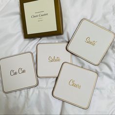 four square coasters sitting on top of a white bed next to a brown box