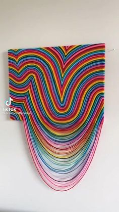 a colorful wall hanging on the side of a white wall next to a computer screen