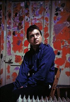 a man sitting on a chair in front of a wall with paint splatters