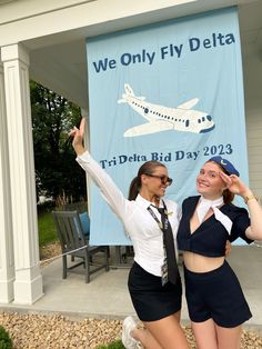 two women in uniform posing for a photo with a banner behind them that says we only fly delta