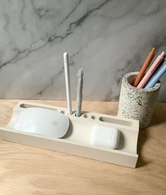 an apple pencil holder with three different pens and two other items in it on a table