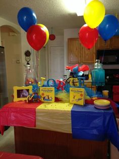 a birthday party with balloons and toys on the table in front of the kitchen area