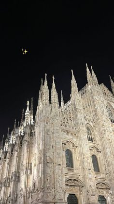 an airplane is flying over the cathedral at night