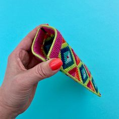 a woman's hand holding a colorful object on a blue background