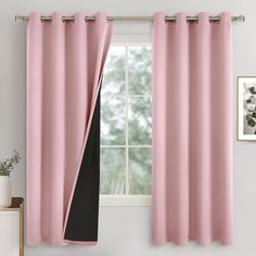 a pink curtain hanging in front of a window next to a potted plant on a table