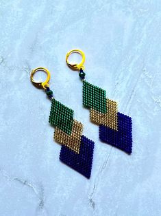 two pairs of beaded earrings sitting on top of a white surface with gold hoop