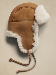 a brown hat with white fur on the side and a leather cord attached to it