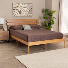 a bed sitting on top of a wooden floor next to a night stand with a lamp