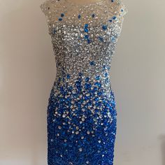 This Statement Piece Is A Short Dress Embellished With Beadwork Throughout Its Fitted Silhouette. It Features A Side Cut And Backless Design. It Is Lined With A Soft And Comfortable Stretchy Fabric. Blue Embellished Sequin Dress For Gala, Blue Evening Dress With Contrast Sequin For Wedding, Glamorous Blue Rhinestone Dress, Blue Sleeveless Dresses With Contrast Sequin, Blue Sleeveless Dress With Contrast Sequin, Elegant Blue Dress With Rhinestones, Elegant Blue Dresses With Rhinestones, Blue Embellished Sequin Evening Dress, Elegant Blue Evening Dress With Contrast Sequin