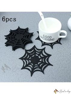 coffee mug coasters with spider web designs on them, one has a spoon in it