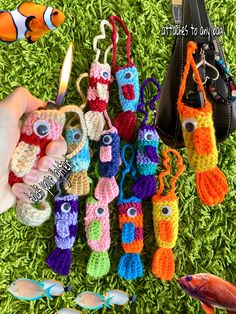 there are many crocheted items laid out on the grass with one hand holding an object