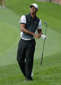 a man holding a golf club on top of a green field