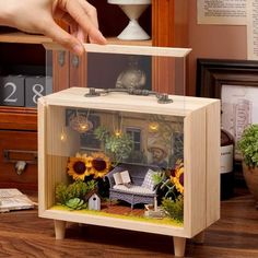 a hand is reaching for the lid on a small cabinet with sunflowers in it