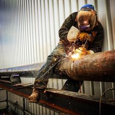 a welder working on an industrial pipe