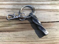 a metal keychain that is on top of a wooden table and has scissors attached to it