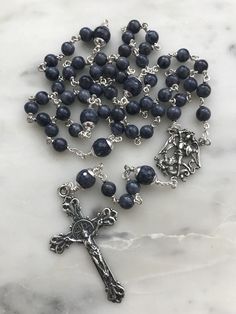 This is a beautiful rosary! The weight is substantial and feels wonderful in your hands. The rosary is handmade with 20 gauge argentium silver wire, sterling silver chain and bead rings; and sterling silver bead caps and rosary medals. The stones are 6mm and 8mm sapphire gemstones. You won't be disappointed with this beauty! Silver Rosary With Natural Stones As A Gift, Silver Rosary With Natural Stones For Gift, Handmade Silver Rosary For Healing, Silver Spiritual Rosary For Healing, Spiritual Sterling Silver Rosary With 8mm Beads, Silver Rosary With 8mm Beads For Healing, Sterling Silver Spiritual Rosary With Crucifix, Blue Gemstone Beads Rosary For Spiritual Use, Silver Rosary With Natural Stones And Round Beads