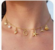 a woman wearing a gold necklace with seashells and starfish charms