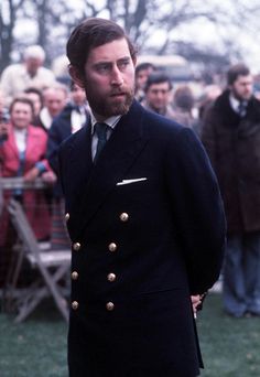 a man wearing a suit and tie standing in front of a large group of people