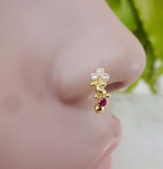 a close up view of a gold nose ring with two small white and red stones