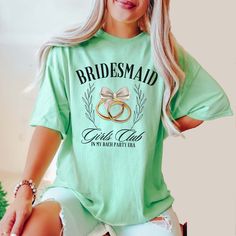 a woman sitting on top of a stool wearing a green shirt with two gold wedding rings