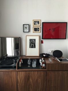 an old record player sits on top of a wooden cabinet in front of some framed pictures