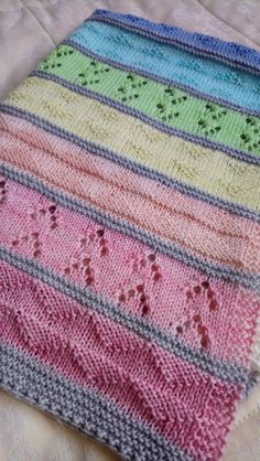 a multicolored knitted blanket sitting on top of a bed