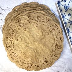 four brown doily plates sitting on top of a white marble counter next to a blue and white plate